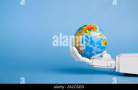 Earth globe in robotic hand, blue panorama background Stock Photo