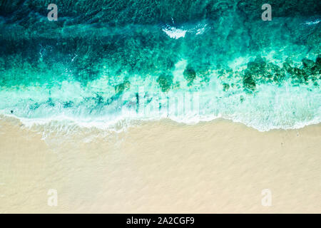 Aerial view looking down onto a tranquil cove with large waves breaking onto the beach Stock Photo