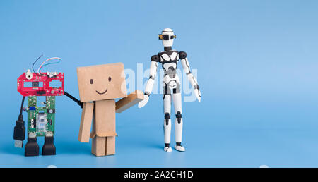 Three robots made with different materials on blue background, free space Stock Photo