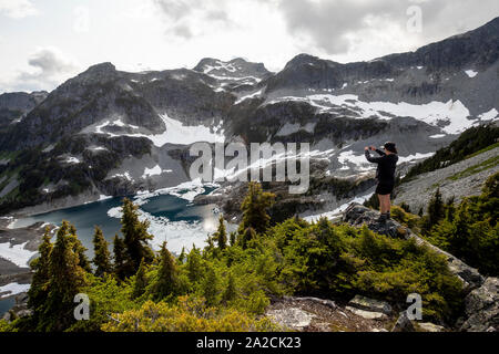 A women takes a cellphone photo of mountains. Stock Photo