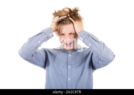 Frustrated teenage boy messing up and pulling his hair, hands to head, looking down shouting and screaming, isolated over white background with copy s Stock Photo