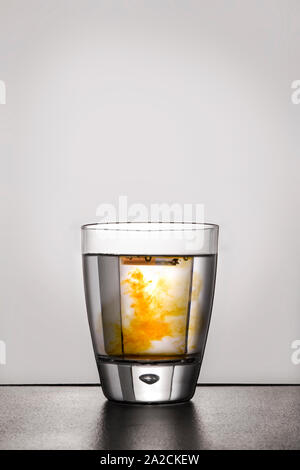 Cigarette in glass of water contaminated with nicotine. Stock Photo