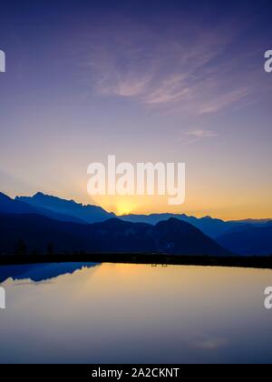 Mountain silhouettes are reflected in an artificial mountain lake at sunset, Hochkalter, Reiteralpe, Berchtesgadener Alps, National Park Stock Photo