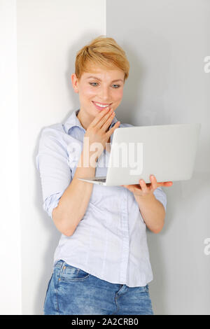 Attractive young woman using her laptop computer smiling Stock Photo