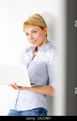 Attractive young woman using her laptop computer smiling Stock Photo