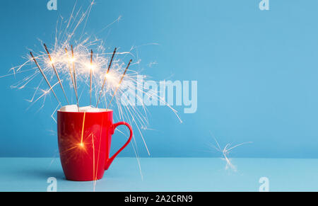 Cocoa and marshmallow in Red cup with sparklers on blue Stock Photo