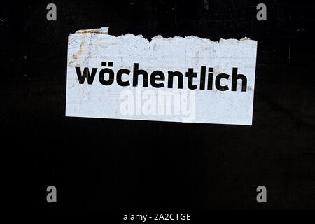 the word weekly written in german language on a white paper sign, translated weekly Stock Photo