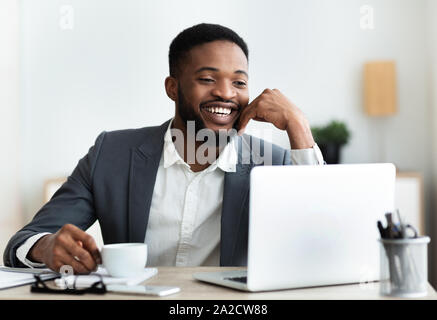 Cheerful african american employee sitting at workplace in modern office Stock Photo