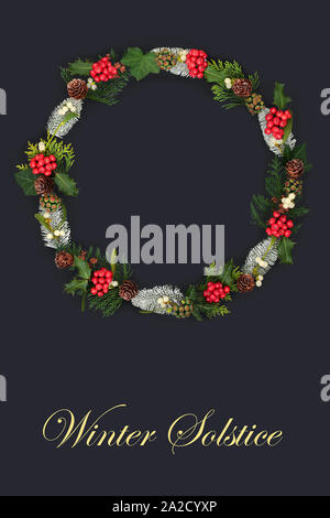 Natural winter solstice wreath with holly and a variety of flora and fauna on dark grey background and title. Stock Photo