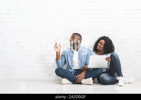 Young couple with laptop pointing at empty space Stock Photo