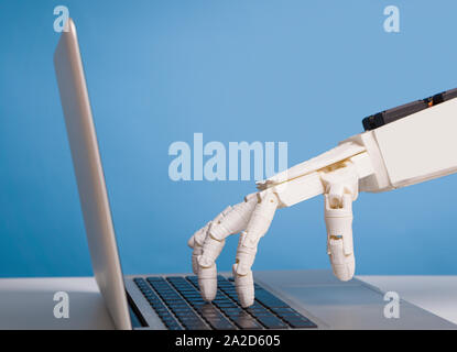 Robotic hand typing on laptop keyboard, free space Stock Photo