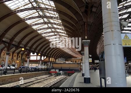 York railway station roof with wrought iron arches and cast iron support columns curving round the station platforms in York Yorkshire England Stock Photo