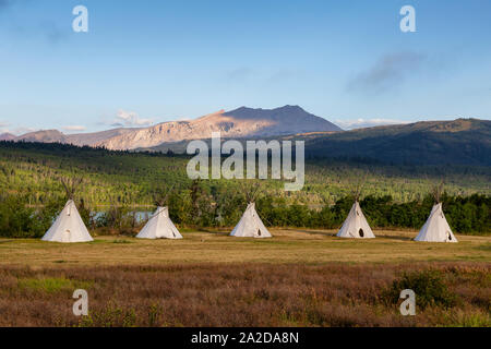 Beautiful View of the Tipi in a field with American Rocky Mountain Landscape in the background during a sunny summer morning. Taken in Montana near Gl Stock Photo