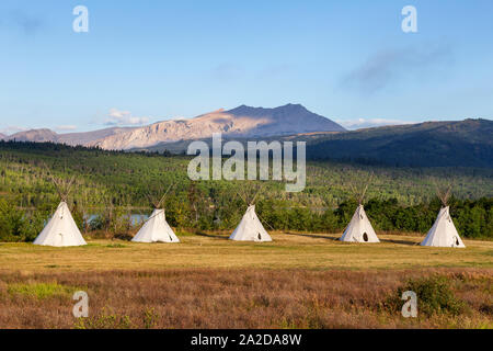 Beautiful View of the Tipi in a field with American Rocky Mountain Landscape in the background during a sunny summer morning. Taken in Montana near Gl Stock Photo