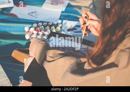 A young lady is drawing outdoors on a sunny day. Stock Photo