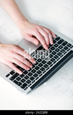 Woman's hands typing on a laptop keyboard Stock Photo