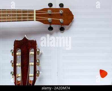 Guitar and ukulele. Wooden instruments. Hawaiian guitar. Light music. Notes and strings. Acoustic instruments. Guitar fretboard. Nylon strings. Stock Photo