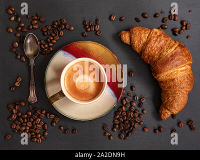Croissant with Coffee cup and coffee beans on grey slate background. Top view. Stock Photo