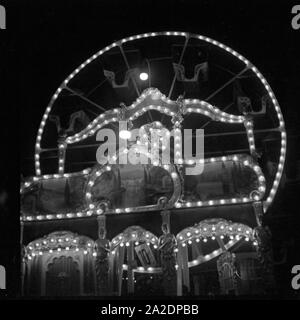 Ein kleines Riesenrad auf dem Weihnachtsmarkt am Abend, Deutschland 1930er Jahre. A little Ferris wheel at the christmas market by night, Germany 1930s. Stock Photo