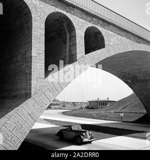 Mit dem Ford Eifel auf unter einer Brücke auf der Reichsautobahn, Deutschland 1930er Jahre. A Ford model Eifel under a bridge at the Reichsautobahn highway, Germany 1930s. Stock Photo