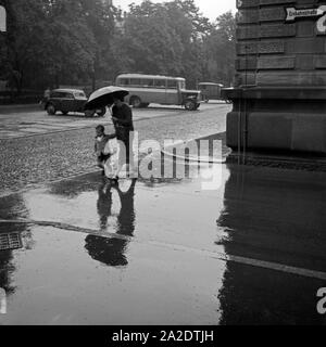 Mutter und Kind im Regen unter einem Regenschirm, Deutschland 1930er Jahre. Mother and child in the rain under an umbrella, Germany 1930s. Stock Photo