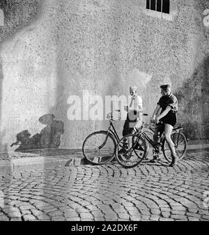 Ein Hitlerjunge und ein BDM Mädel auf ihren Fahrrädern in einer Gasse in Braunschweig, Deutschland 1930er Jahre. A Hitler youth and a BDM girl on their bicycles in a lane of Braunschweig, Germany 1930s. Stock Photo