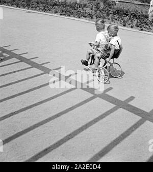 Zwei kleine Jungen fahren auf einem Dreirad in Chemnitz, Deutschland 1930er Jahre. Two little boys riding a tricycle at Chemnitz, Germany 1930s. Stock Photo