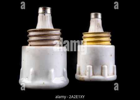 Old white ceramic electric fuse. Electrical surge protection. Dark background. Stock Photo