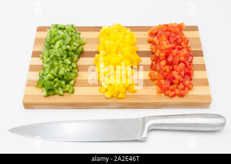 Red, green and yellow sweet bell peppers chopped on a wooden cutting board and a cutting knife Stock Photo
