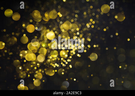 Abstract blurred glitter bokeh background in gold, on black. Festive shiny backdrop Stock Photo