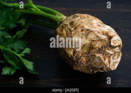 Celery Root with Stems and Leaves: Raw celeriac bulb with stems and leaves on a dark wood background Stock Photo