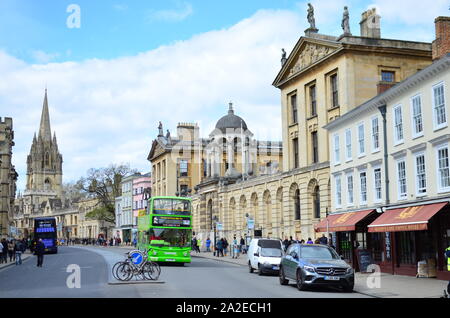 The High street in Oxford with moving green double decker bus and parked bicycle. View on The Queen's College and Church of St. Mary the Virgin Stock Photo