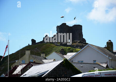 The ruins of Criccieth Castle towering over houses with its Welsh flags flying in North Wales. Stock Photo