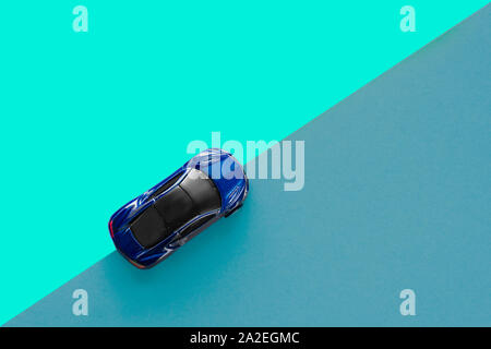 Kids toy car on trendy colorful background. Baby blue car top view on double colored blue paper. Boys game. Travel and sport lifestyle. Business Stock Photo