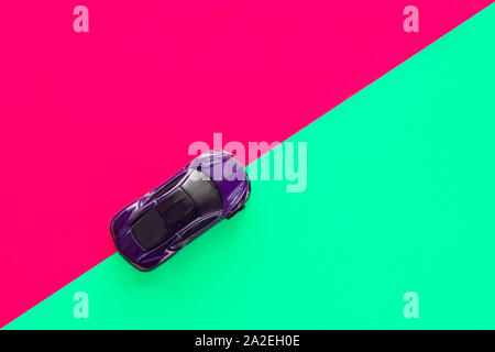 Kids toy car on trendy colorful background. Baby car top view on green and pink colored paper. Boys game. Travel and sport lifestyle. Business Stock Photo