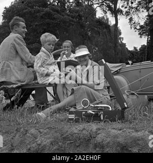 Ein Mann, zwei Frauen und ein kleiner Junge sitzen an einem Klapptisch vor einem Zelt, Deutschland 1930er jahre. A man, a little boy and two women sitting at a folding table in front of a tent, Germany 1930s. Stock Photo