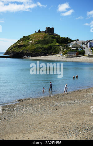 Holiday makers enjoy the beach with Criccieth Castle high up looking over the county of Gwynedd in North Wales Stock Photo