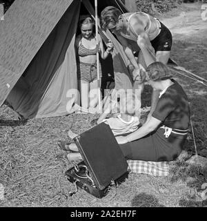 Eine Familie hat beim Campingausflug das Electrola Koffer 106 Grammophon mitgenommen, Deutschland 1930er Jahre. A family listening to the Electrola Koffer 106 suitcase gramophone on a camping trip, Germany 1930s. Stock Photo