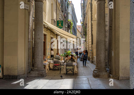 People eating outside a restaurant along Via Conte Verde,a narrow street in Turin,Italy Stock Photo