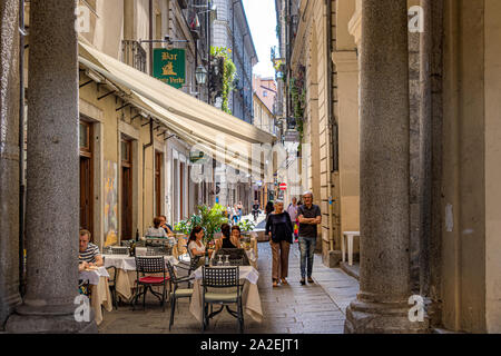 People eating outside a restaurant along Via Conte Verde,a narrow street in Turin,Italy Stock Photo