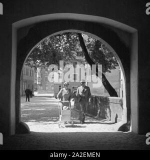 Ein Paar geht mit einem Kinderwagen durch einen Torbogen in Dinkelsbühl, Deutschland 1930er Jahre. A couple with a pram walking through an archway at Dinkelsbuehl, Germany 1930s. Stock Photo