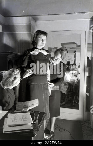 Ein Model bei der Anprobe eines Kleides mit Modesch?pferin Annemaria Geise und einer Assistentin im Studio; Deutschland ca. 1939. A Model trying a dre Stock Photo