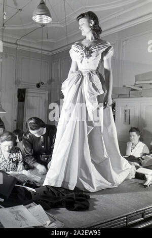 Ein Model und Schneiderinnen bei der Anprobe eines Kleides von Modesch?pferin Annemaria Geise; Deutschland ca. 1939. A Model and tailors trying a dres Stock Photo