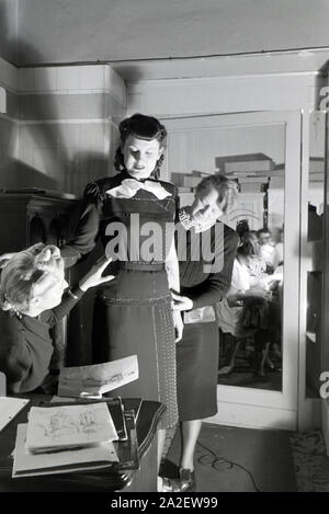 Ein Model bei der Anprobe eines Kleides mit Modesch?pferin Annemaria Geise und einer Assistentin im Studio; Deutschland ca. 1939. A Model trying a dre Stock Photo