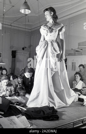 Ein Model und Schneiderinnen bei der Anprobe eines Kleides von Modesch?pferin Annemaria Geise; Deutschland ca. 1939. A Model and tailors trying a dres Stock Photo
