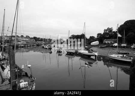 Looking upstream near the mouth of River Seiont in Caernarfon Harbour with several yachts moored and some still dry on the river bed as tide rises Stock Photo