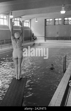 Junge Frau auf dem Sprungturm im Schwimmbad, Freudenstadt, Deutschland 1930er Jahre. Young woman standing on the diving tower in a swimming pool, Freudenstadt, Germany 1930s. Stock Photo