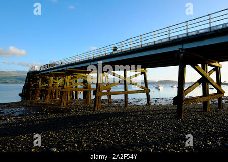 A view under Beaumaris Pier showing the wooden supports substructure at low tide in the evening sunshine Stock Photo