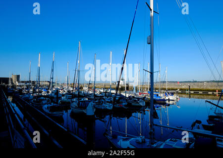 Victoria Dock Caernarfon North Wales on a bright sunny morning blue sky calm water reflections of yachts and boats moored Stock Photo