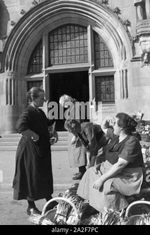 Verkäuferinnen bei einem Gespräch auf dem Wochenmarkt auf dem Stuttgarter Marktplatz, Deutschland 1930er Jahre. Marketers having a chat at the weekly market on the market square in Stuttgart, Germany 1930s. Stock Photo
